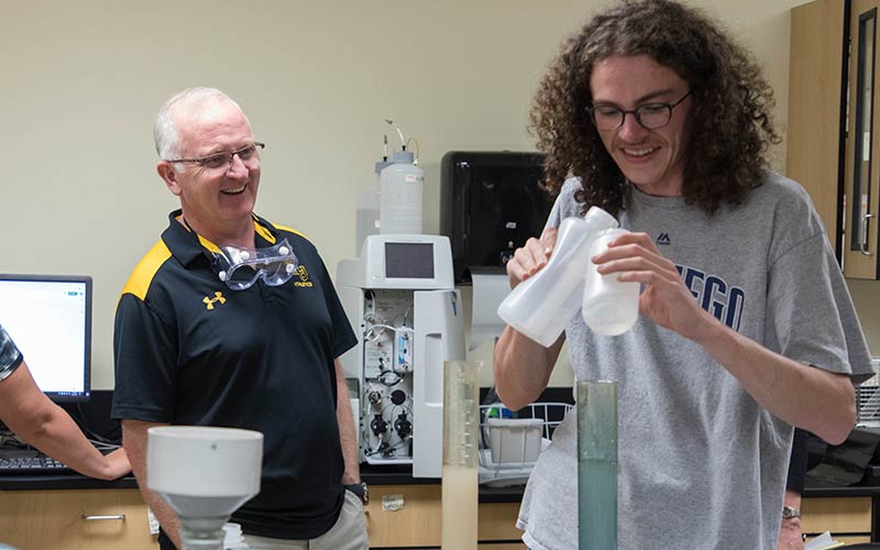 President Allan Belton looking on as a student conducts a test in the Rieke Science Center at Pacific Lutheran University.