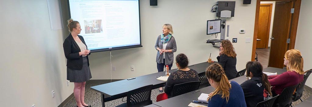 A student and professor speaking in front of a class