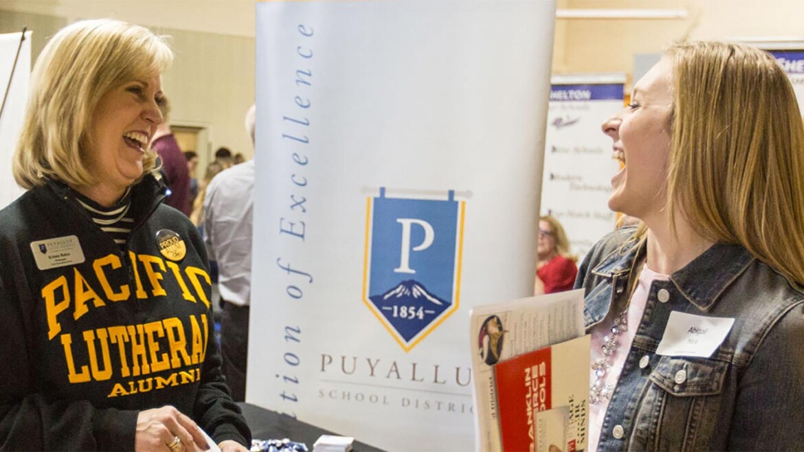 A PLU alum and a PLU student chat and laugh at an event