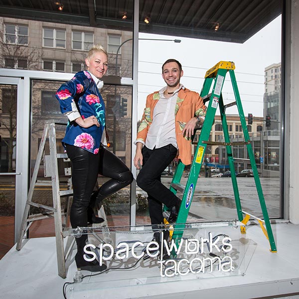 Kate Monty and Dmitry Mikheyev with a neon SpaceWorks sign in downtown Tacoma, Thursday, April 6, 2017. (Photo: John Froschauer/PLU)