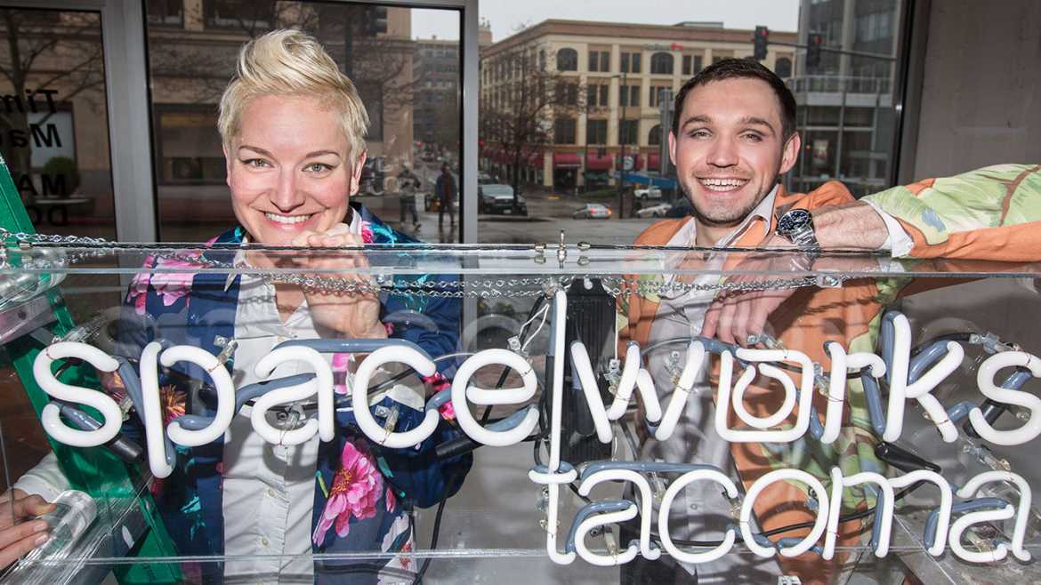 Kate Monty and Dmitry Mikheyev with a neon SpaceWorks sign in downtown Tacoma, Thursday, April 6, 2017. (Photo: John Froschauer/PLU)