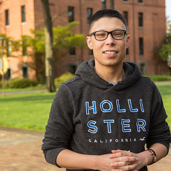 Rhys Jones poses by Harstad Hall at PLU