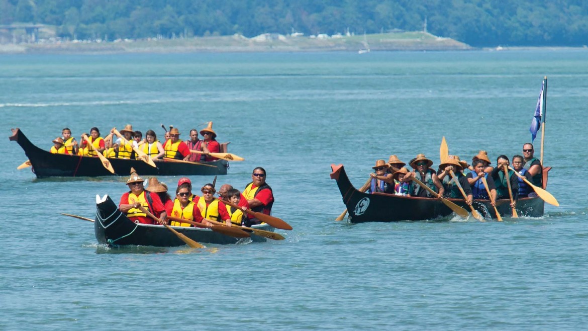 People paddling down the river in canoes participating in the "Power Paddle to Puyallup"