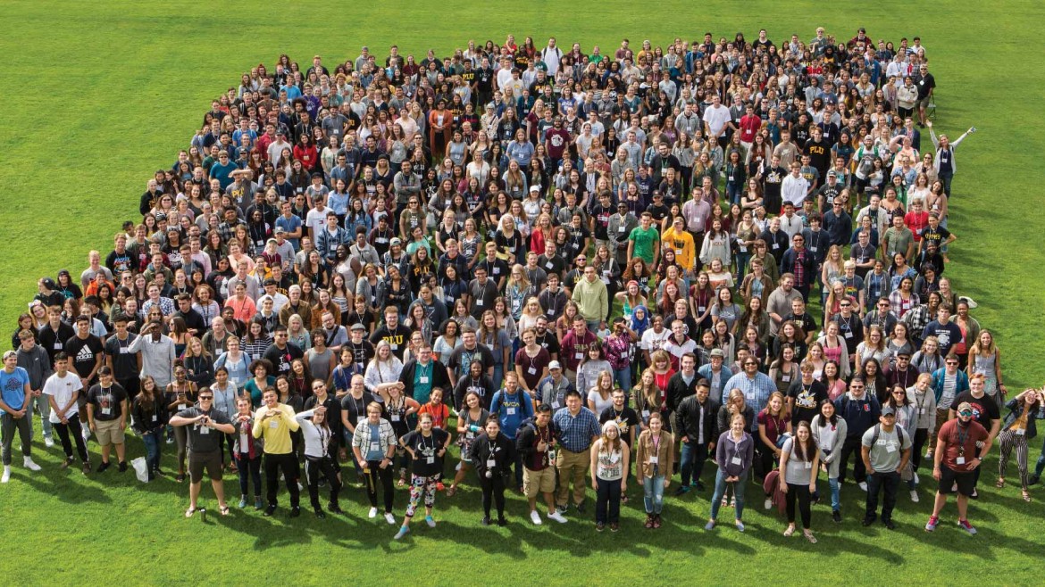 New incoming students gather on Foss Field for a group photo during orientation weekend.