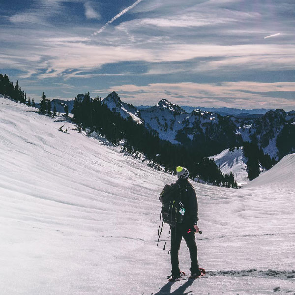 A man is standing on a snow hill up in the mountains