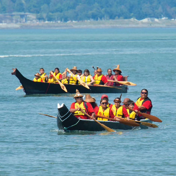 People paddling down the river in canoes participating in the "Power Paddle to Puyallup"