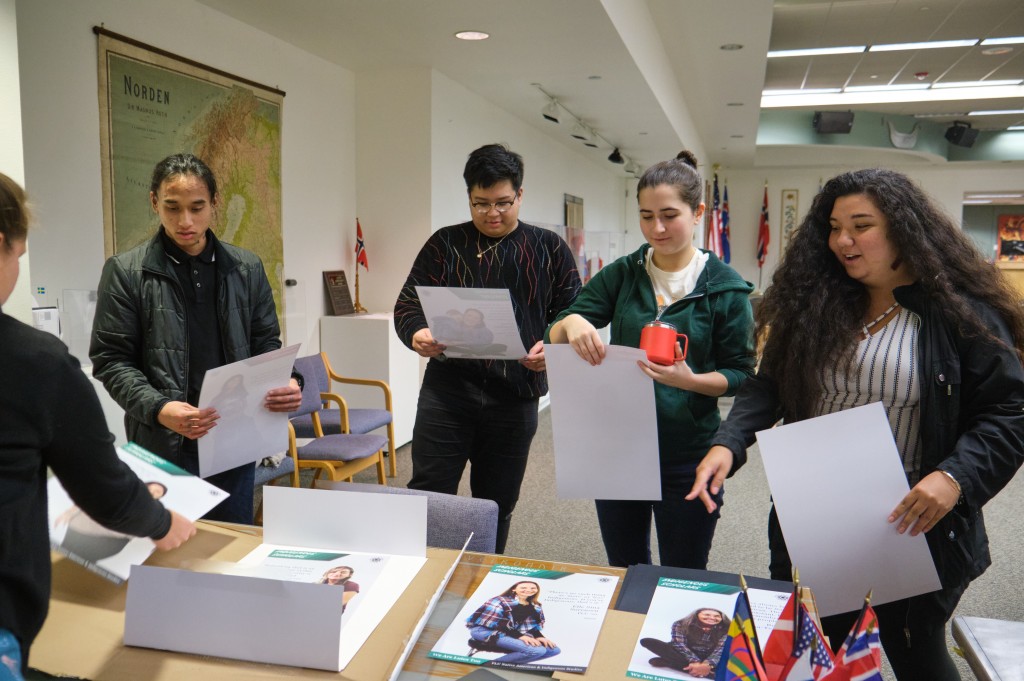 A poster exhibition designed and installed by Native American & Indigenous Studies students Fall 2019 - students standing at a table holding their posters