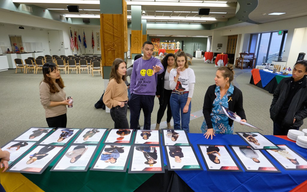 A poster exhibition designed and installed by Native American & Indigenous Studies students Fall 2019 - students looking at their posters on a table