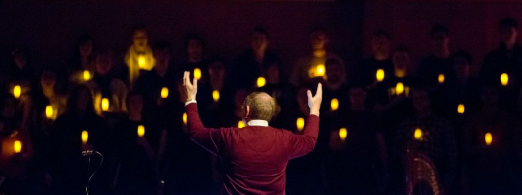 Richard Nance conducting students singing in the dark holding lanterns