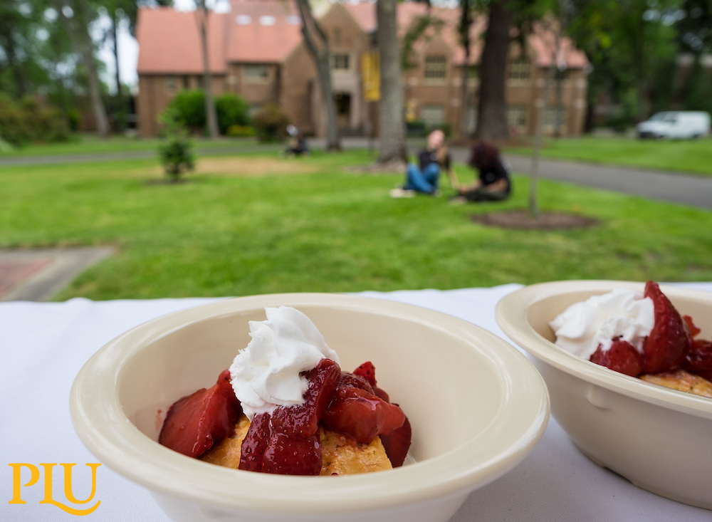 bowl of strawberries and whipped cream on a table next to red square PLU