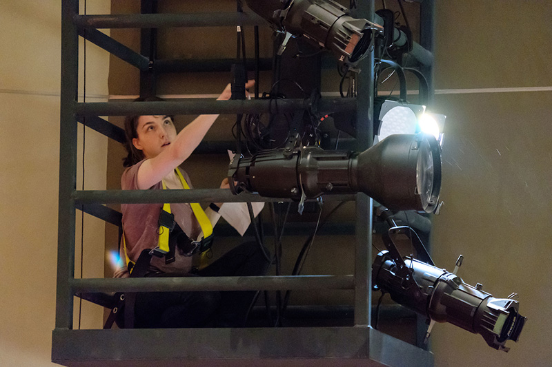 A PLU student hangs and adjusts lights during tech.
