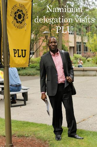 One of the Namibian delegation members standing by a PLU flag on campus