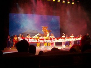 2009 China University Wind Ensemble Tour - Shanghai Acrobatic Troupe on stage, holding a welcome banner for Pacific Lutheran University.