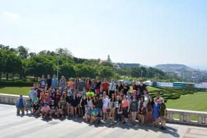 2017 Spain and Portugal University Wind Ensemble Trip - A large group of people standing together outdoors, posing for a photo with mountains in the background, under a clear blue sky.