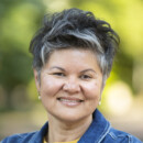 A photo of Dr. Frey wearing a denim jacket and a yellow undershirt. Dr. Frey is happily smiling.